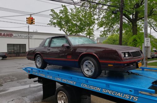 Frame Auto Collision tow truck transporting a classic car on Long Island